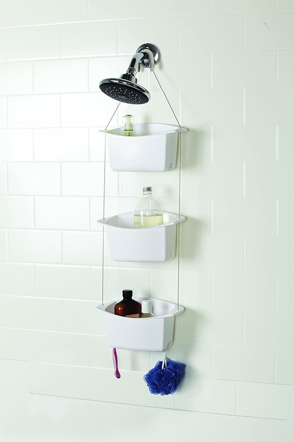 The shower caddy with three storage baskets hanging over the showerhead.