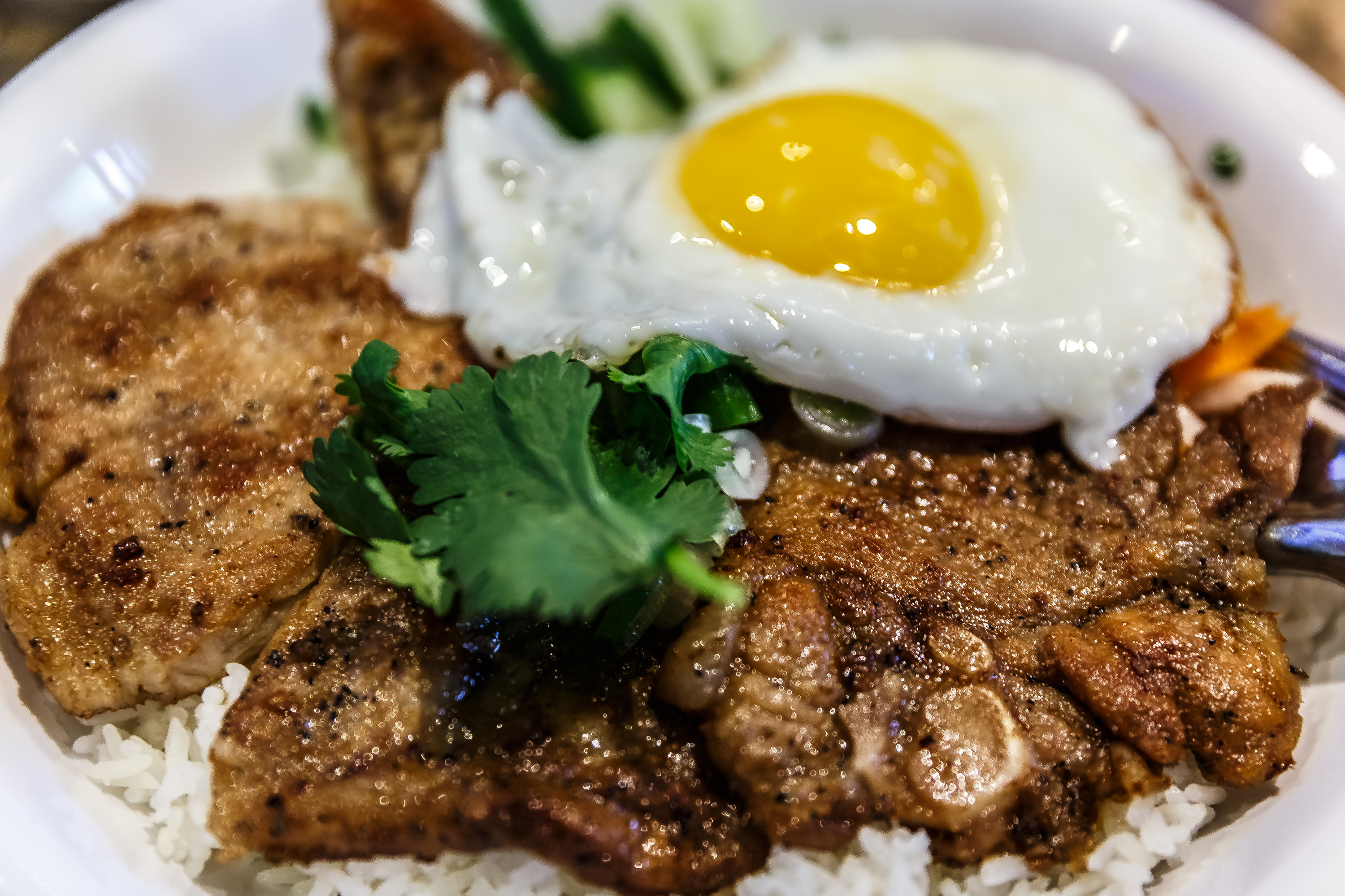 A bed of broken rice covered with greasy pork chops and a fried sunny-side-up egg