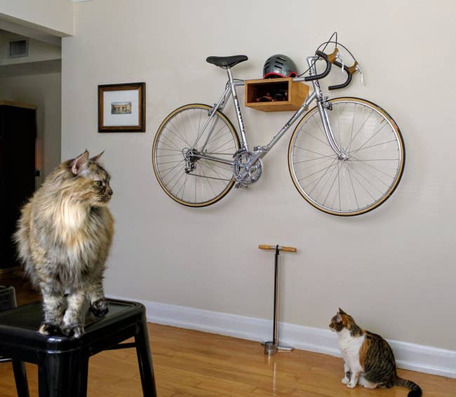 A wooden bike rack mounted to the wall with bike hanging from it