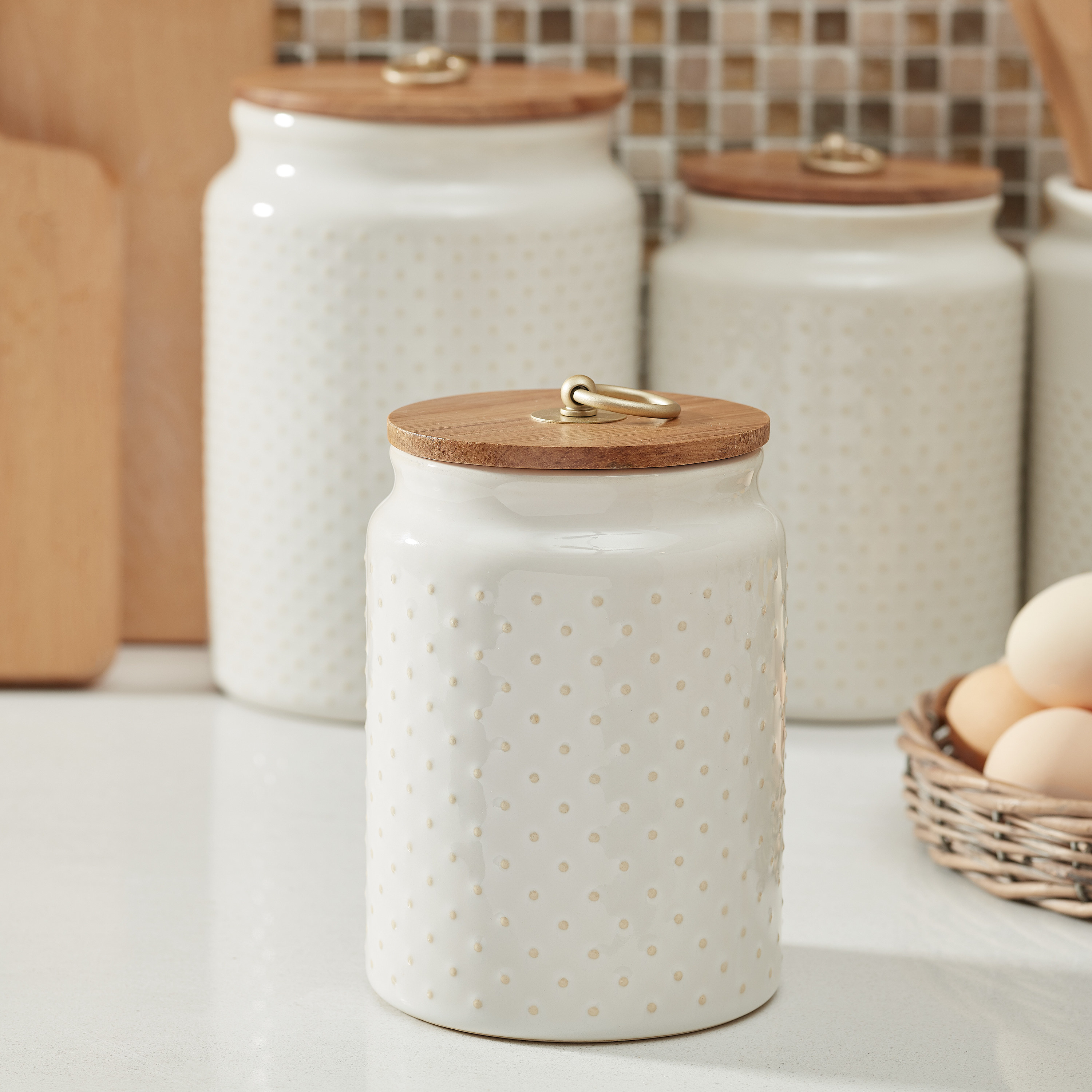 the white canister with tan dots and a wooden lid 