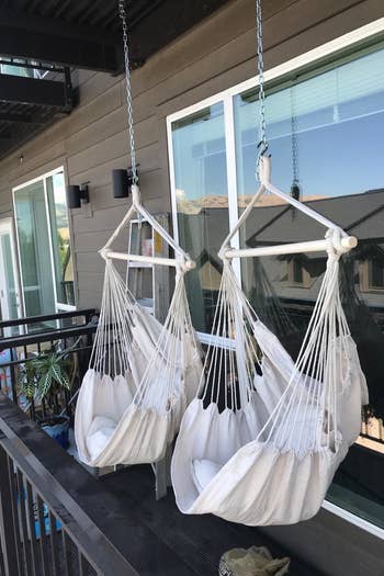 a reviewer photo of a pair of hanging chairs hung from the ceiling of their balcony 