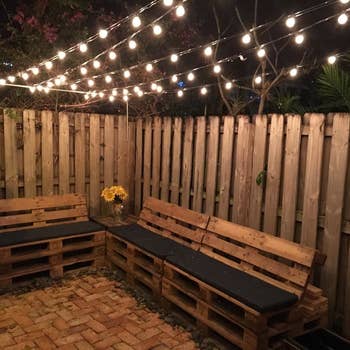 a reviewer photo of a backyard with strings of lights handing above a set of benches 