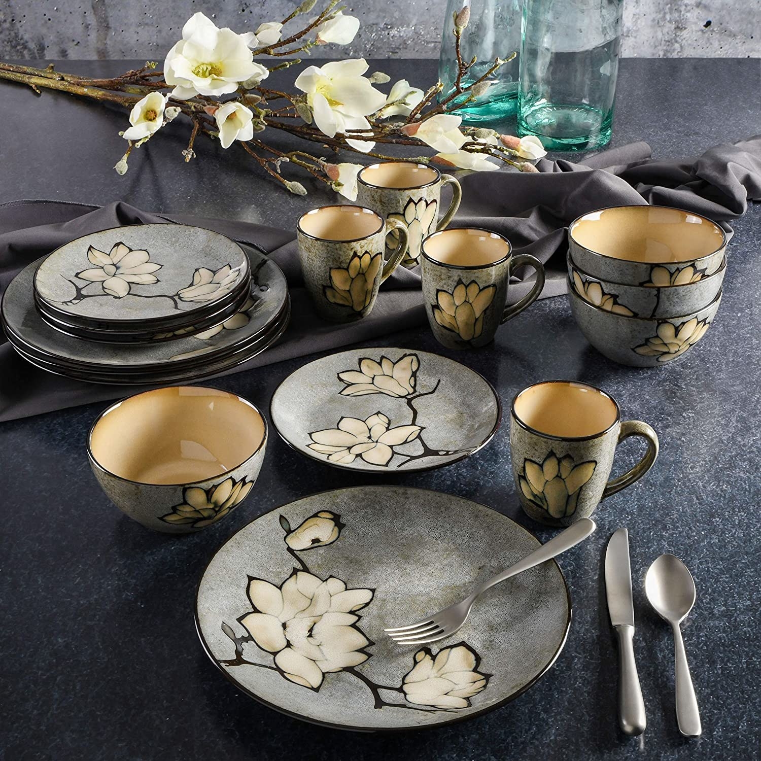 several gray gibson elite plates, bowls and mugs laid out on a table