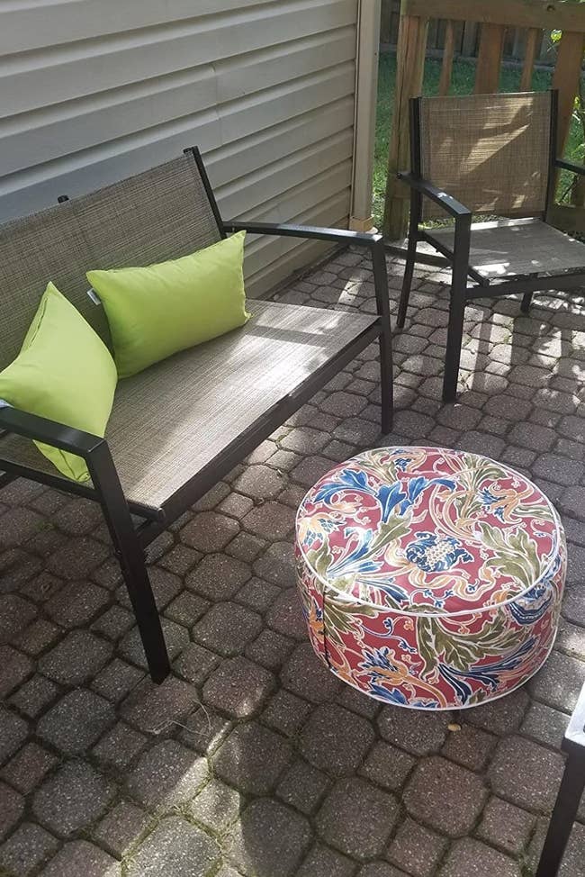 a reviewer photo of a patio chair with a printed ottoman in front to it 