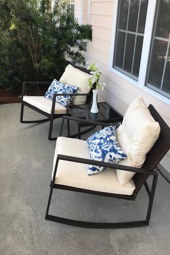 a reviewer photo of the two rocking chairs with cream cushions with a matching side table between 