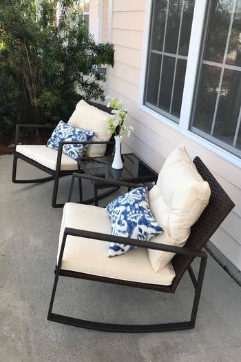 a reviewer photo of the two rocking chairs with cream cushions with a matching side table between 