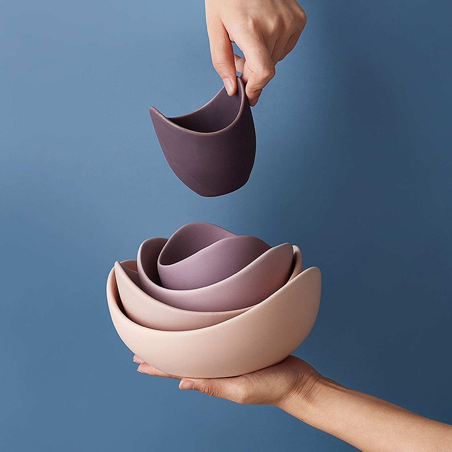 a model&#x27;s hand holding the stacked ceramic lotus bowls