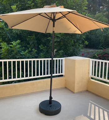 a reviewer photo of the umbrella on a patio in tan 