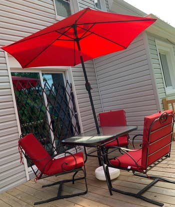 a reviewer photo of a patio dining set with an umbrella in the center of the table in red 