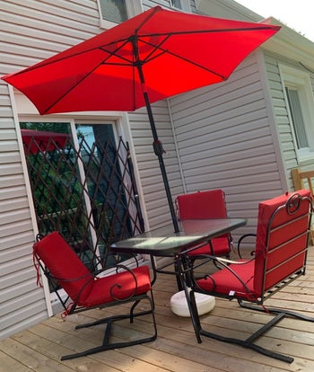 a reviewer photo of a patio dining set with an umbrella in the center of the table in red 