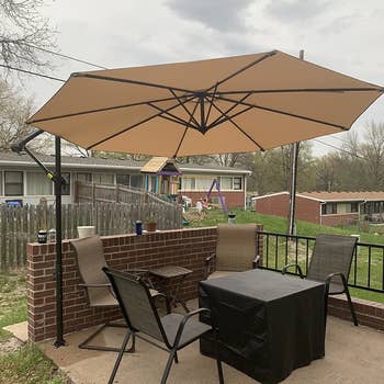 a reviewer photo of a hanging umbrella on a stand over a patio dining set 