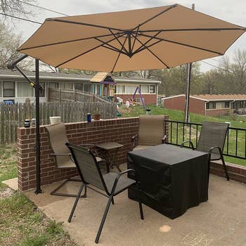 a reviewer photo of a hanging umbrella on a stand over a patio dining set 