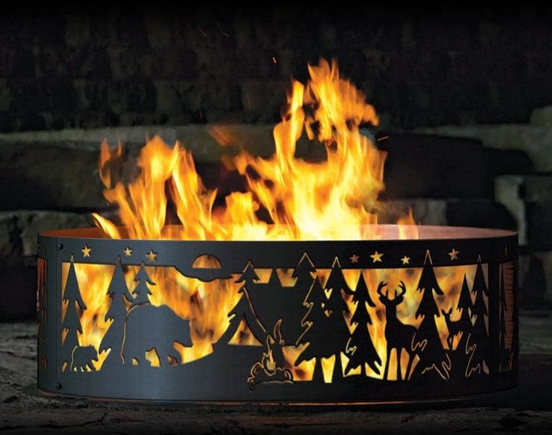 a black metal ring fire pit with a forest and wildlife design cut into the sides 