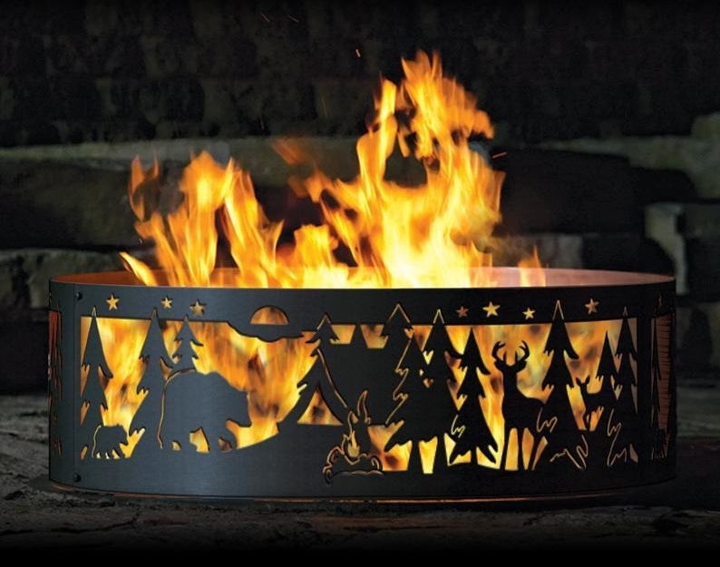 a black metal ring fire pit with a forest and wildlife design cut into the sides 