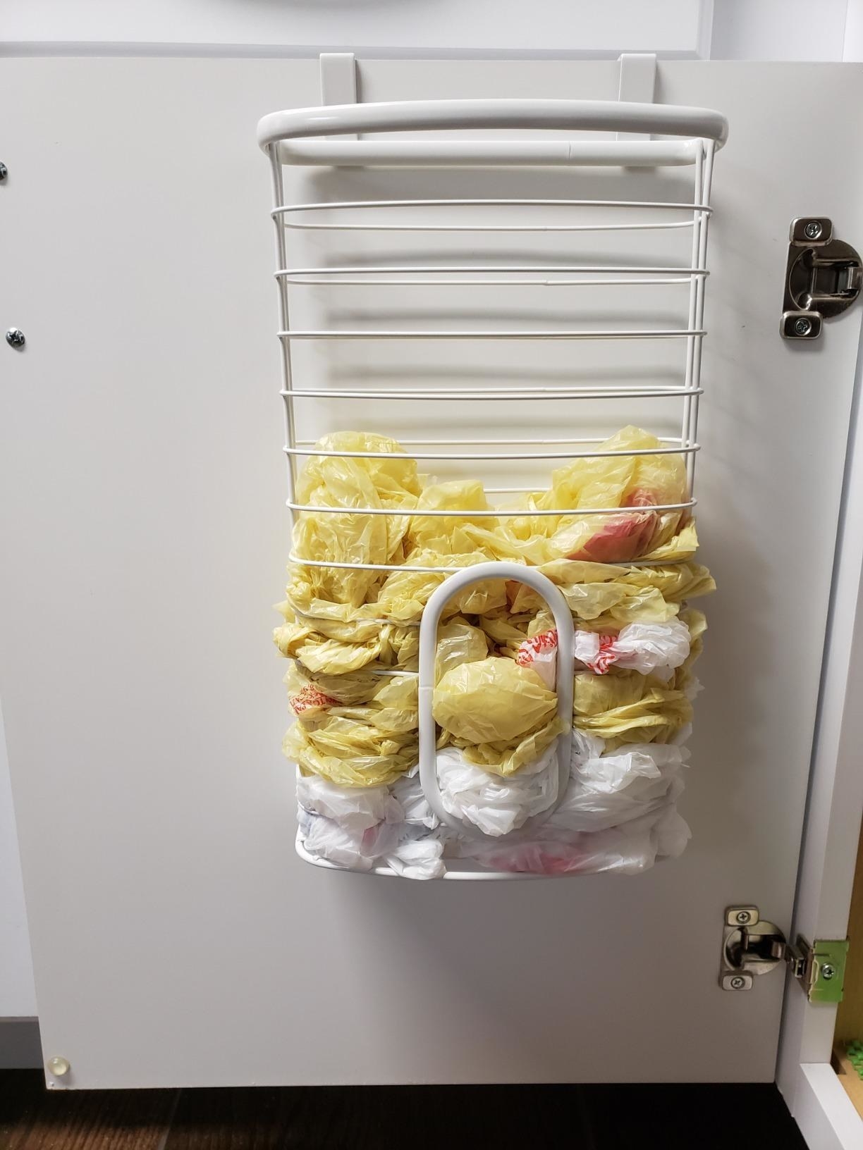 A reviewer photo of the bag organizer, hung on a cabinet below a sink