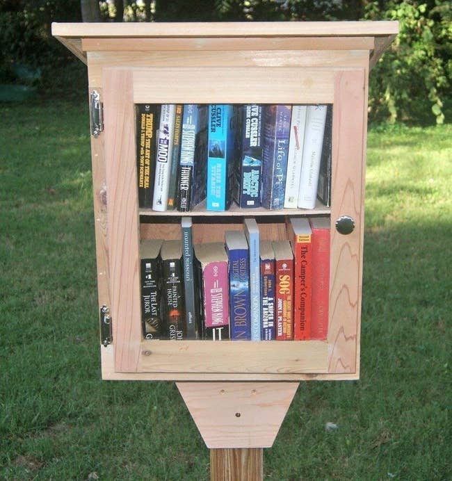 a cedar box on a stake featuring a clear glass door with books inside 