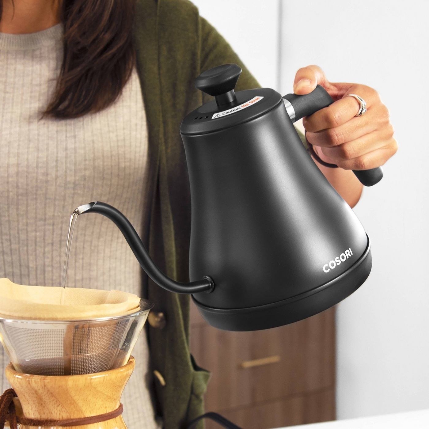 A model uses the black kettle to pour water into a carafe