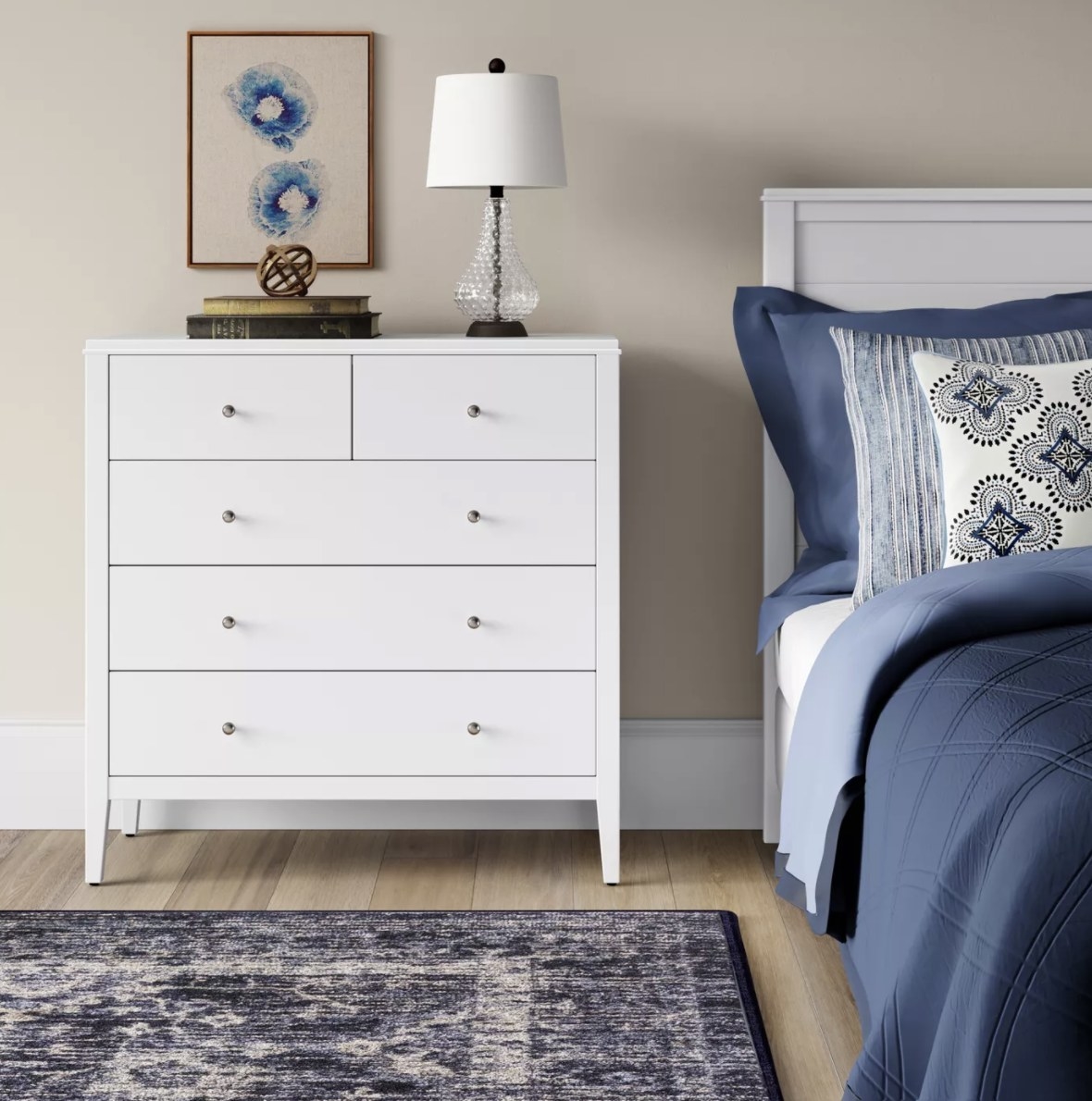 The vertical white dresser has three long rectangular shelves and two smaller rectangular ones at the top
