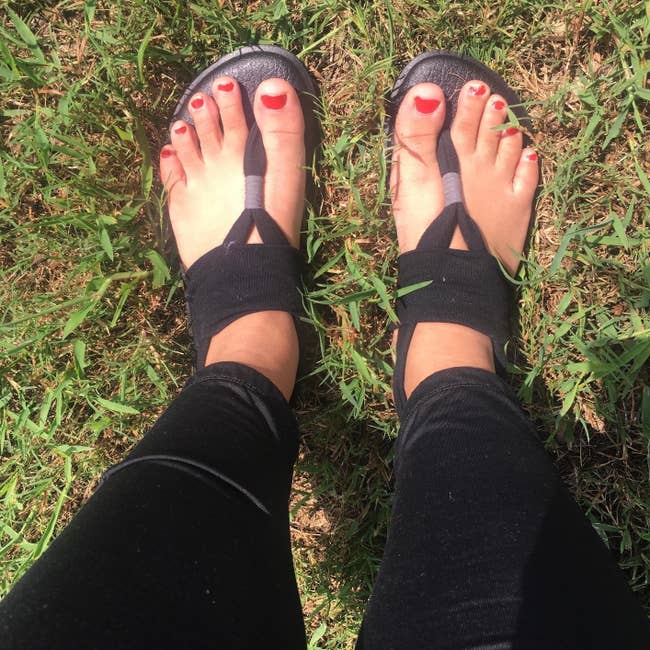 reviewer wearing the flat shoes thong sandals with black soles and black straps