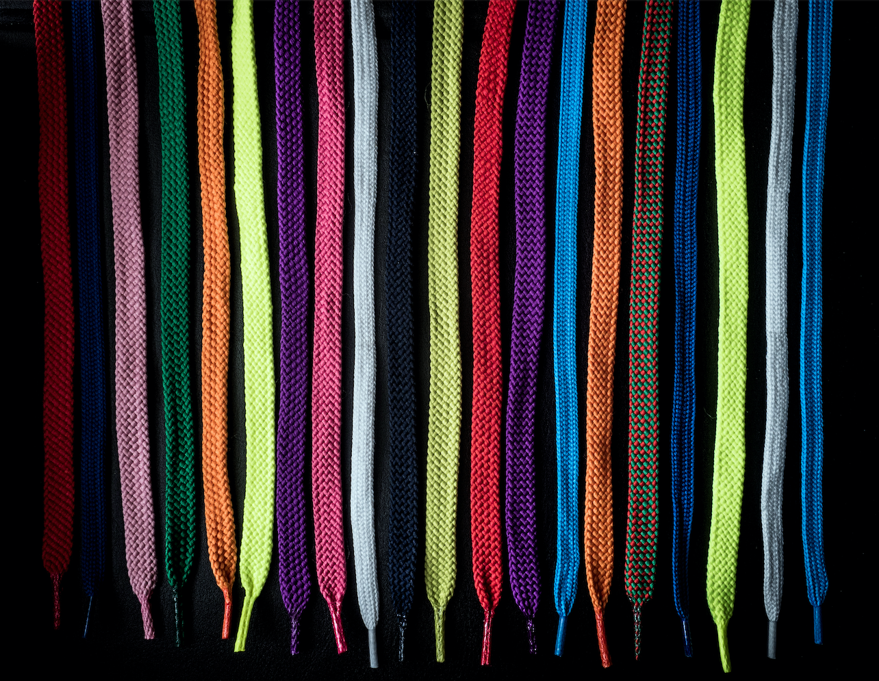 Close-up of multi-colored shoelaces against black background 