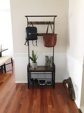 a reviewer photograph of their introduction mode organizer with shoes connected the bottommost a mates of purses hanging from the hooks astatine the apical and a works and decorative missive M sitting connected the shelf