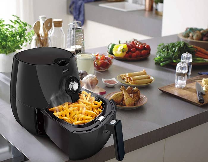 Air fryer with fries inside, kept on a kitchen counter.