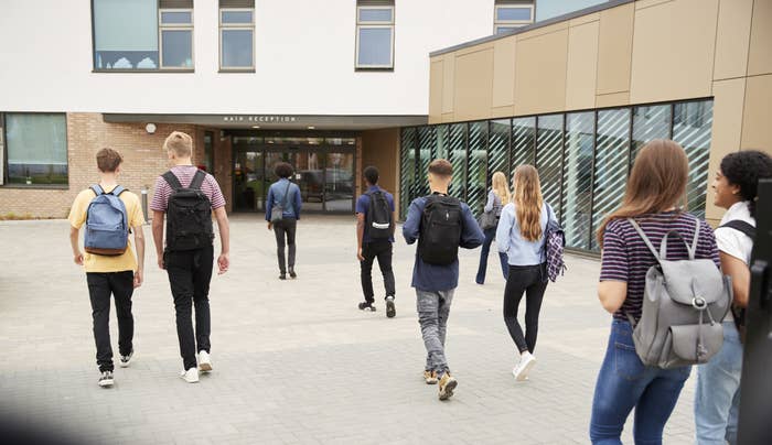 Rear view of high school students walking into a building together