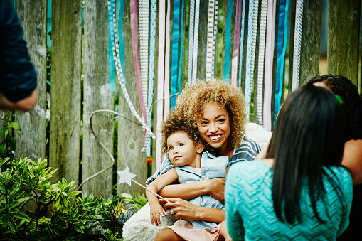 A happy mum clasps her baby at a party.