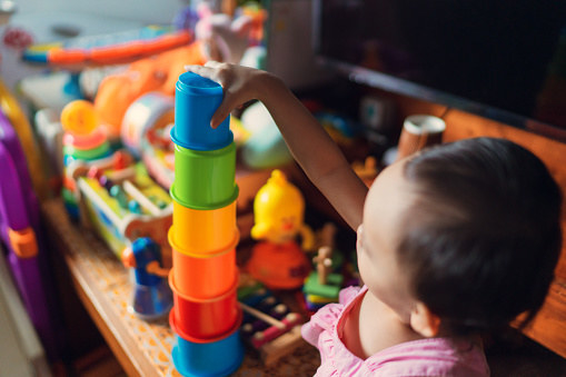 A small child puts a colourful building block on top of another.