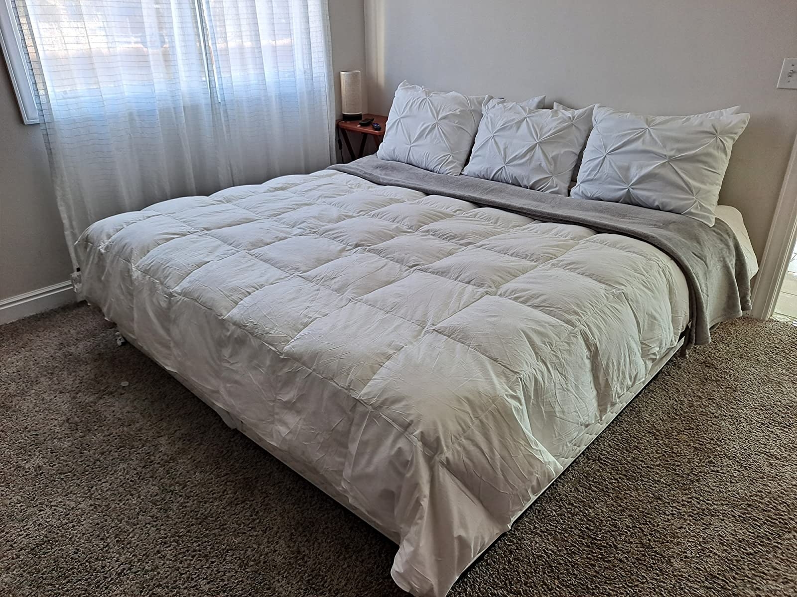The quilted blanket in white on a reviewer&#x27;s king size bed