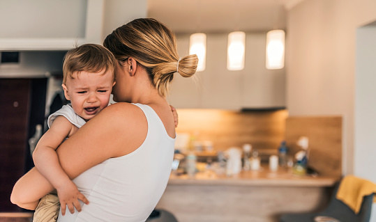 A mother holds an upset baby.