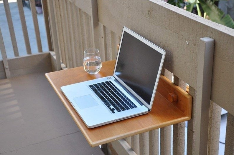 a small table holding a laptop and glass of water