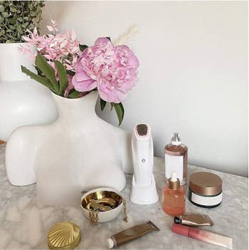 The vase on a vanity table surrounded by makeup and jewelry