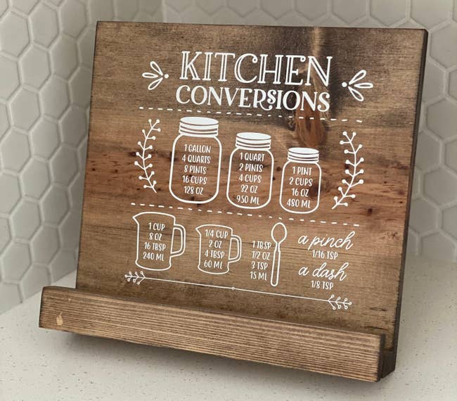 a dark wooden cookbook holder with a white hand-painted kitchen conversions design