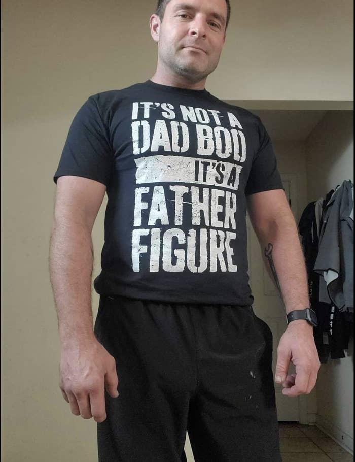 Reviewer in black T-shirt that says &quot;it&#x27;s not a dad bod, it&#x27;s a father figure&quot; in white block text 