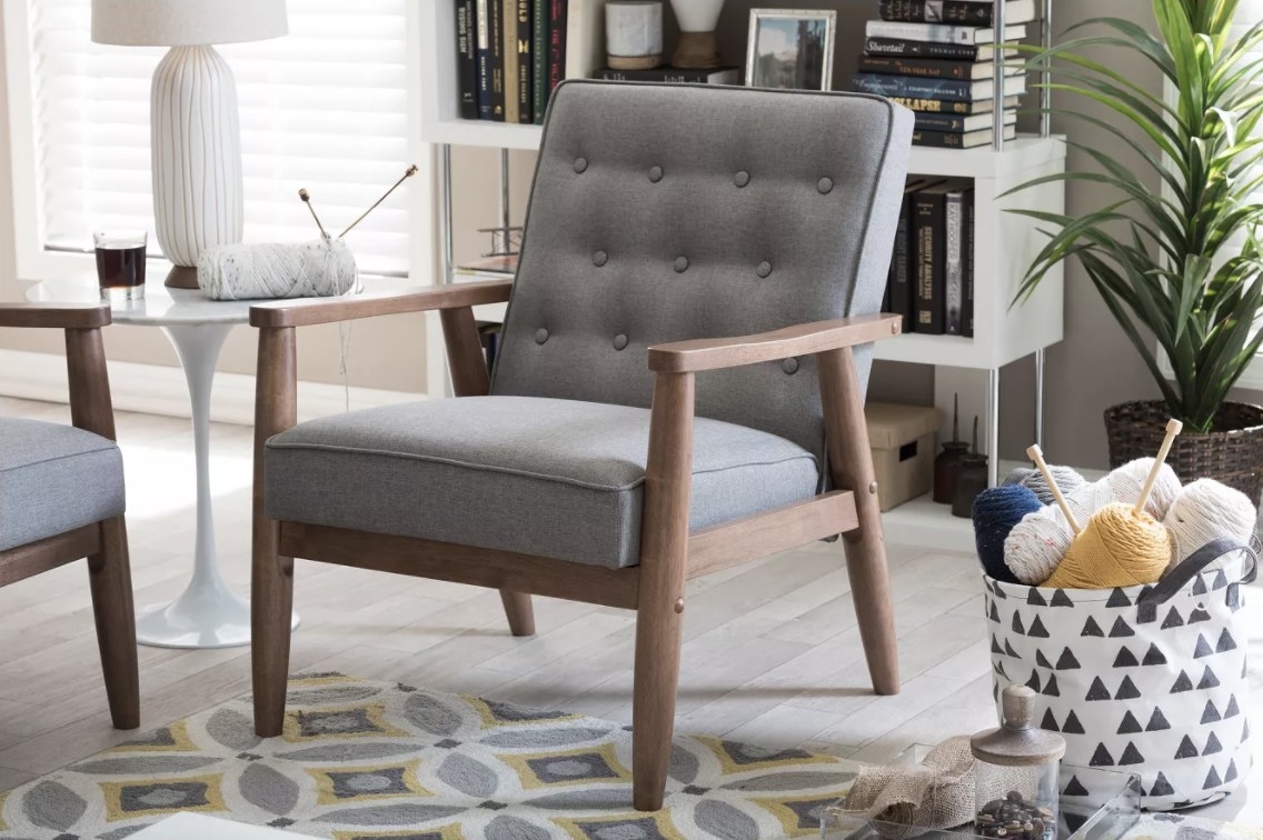 The grey chair has a wooden frame and arms and plush cushions