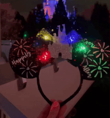 a gif of the black ears with the castle in the middle, lights glowing, and fireworks on them