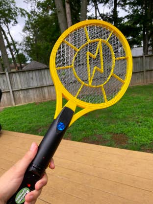 Reviewer holding the tennis-like swatter in a back yard 