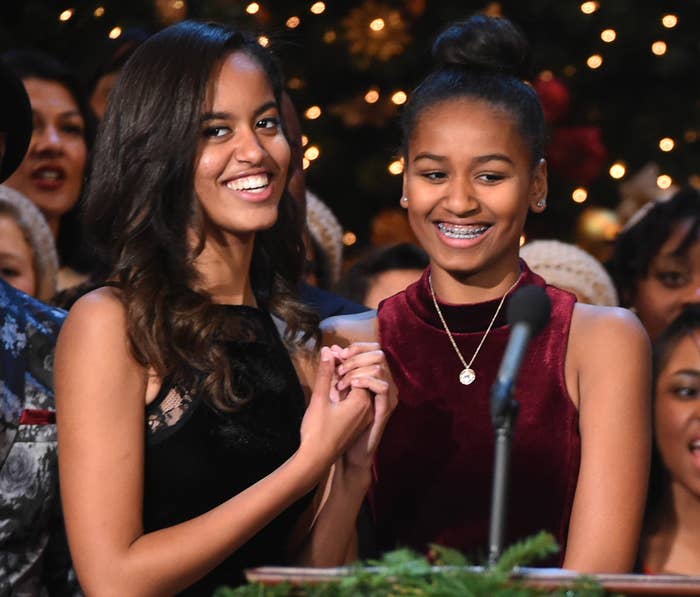 Malia and Sasha smile onstage at an event