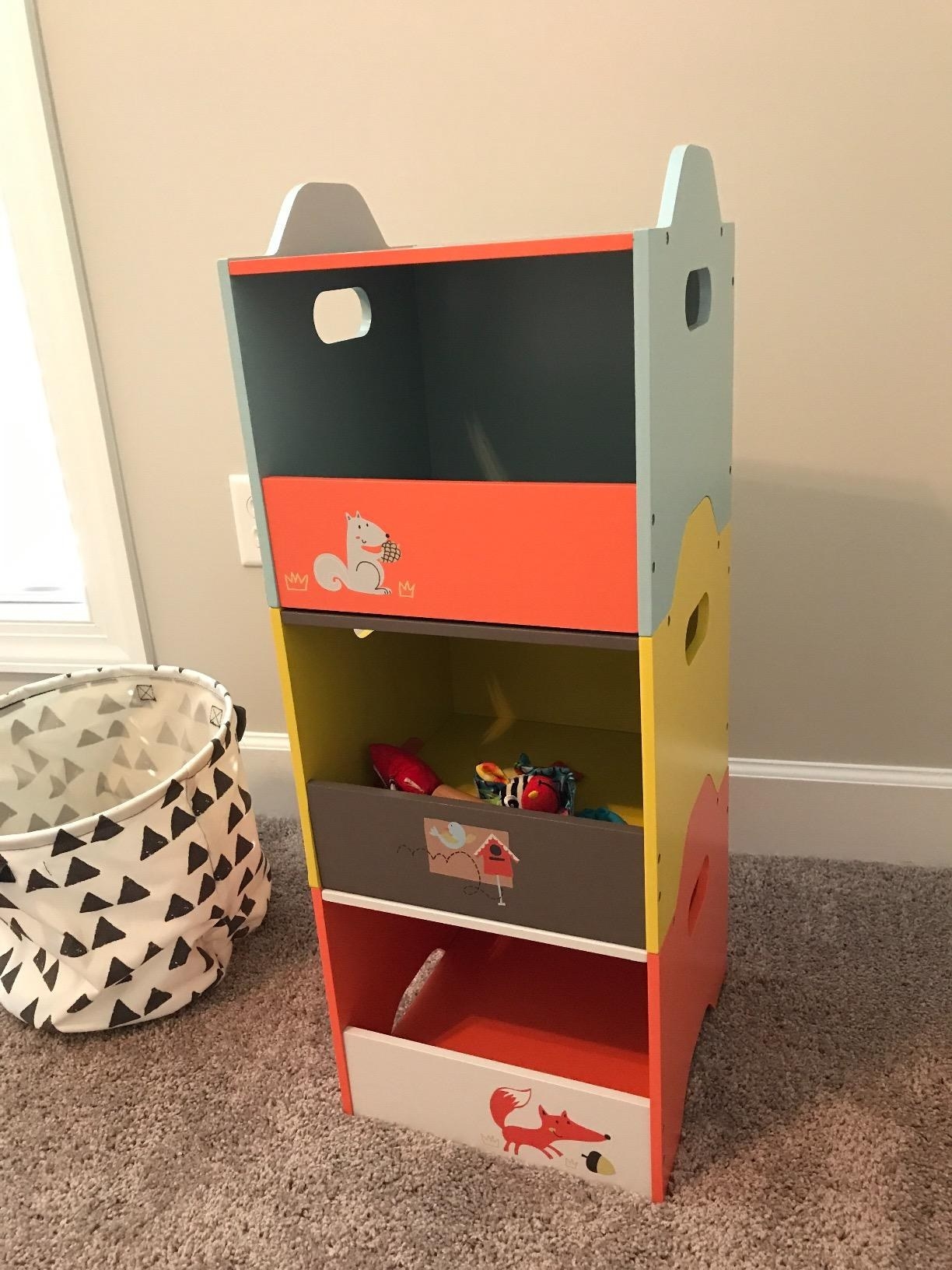 a reviewer&#x27;s three storage bins stacked on top of each other with toys inside
