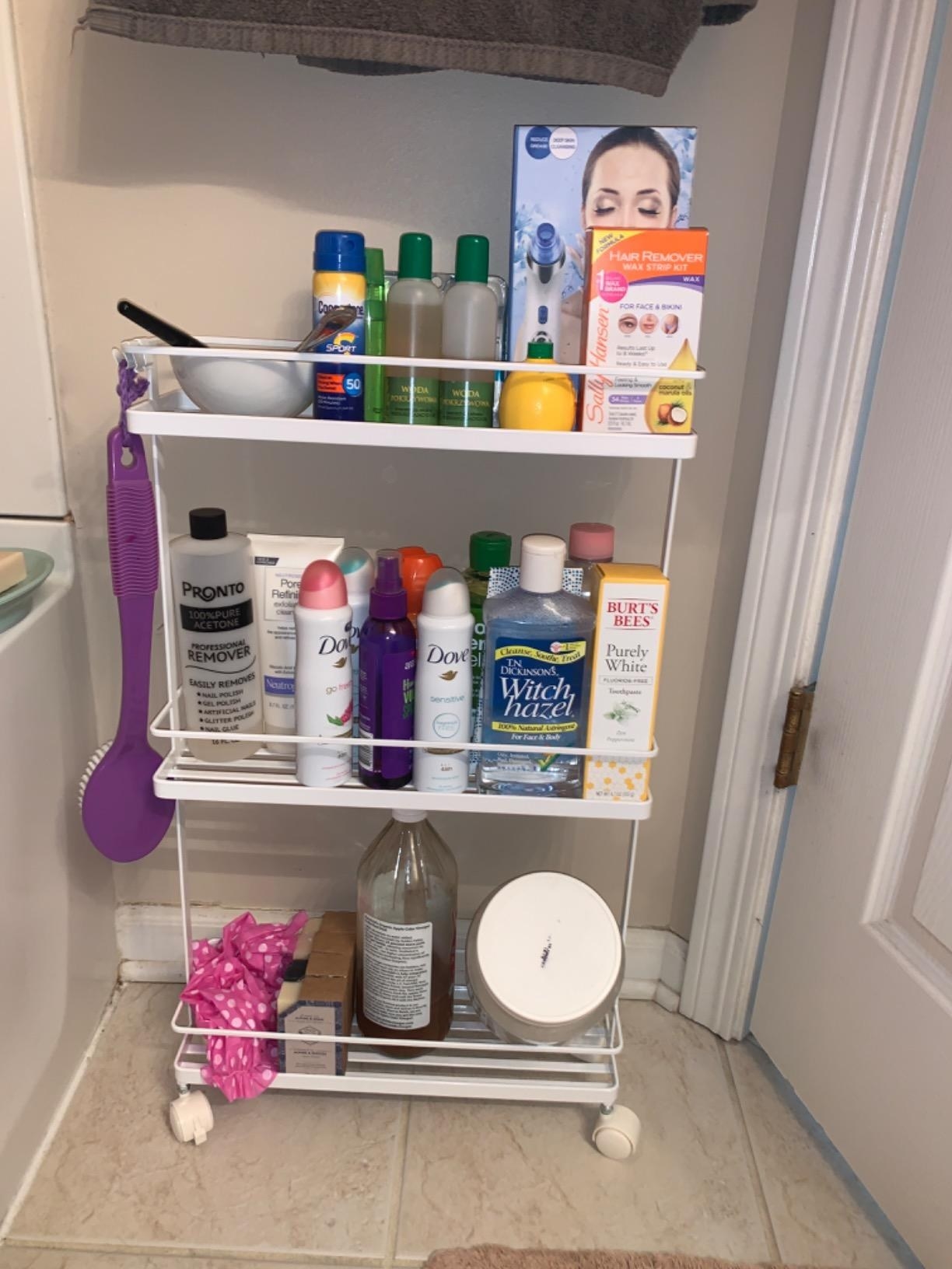 The narrow cart on wheels with three open shelves in a bathroom