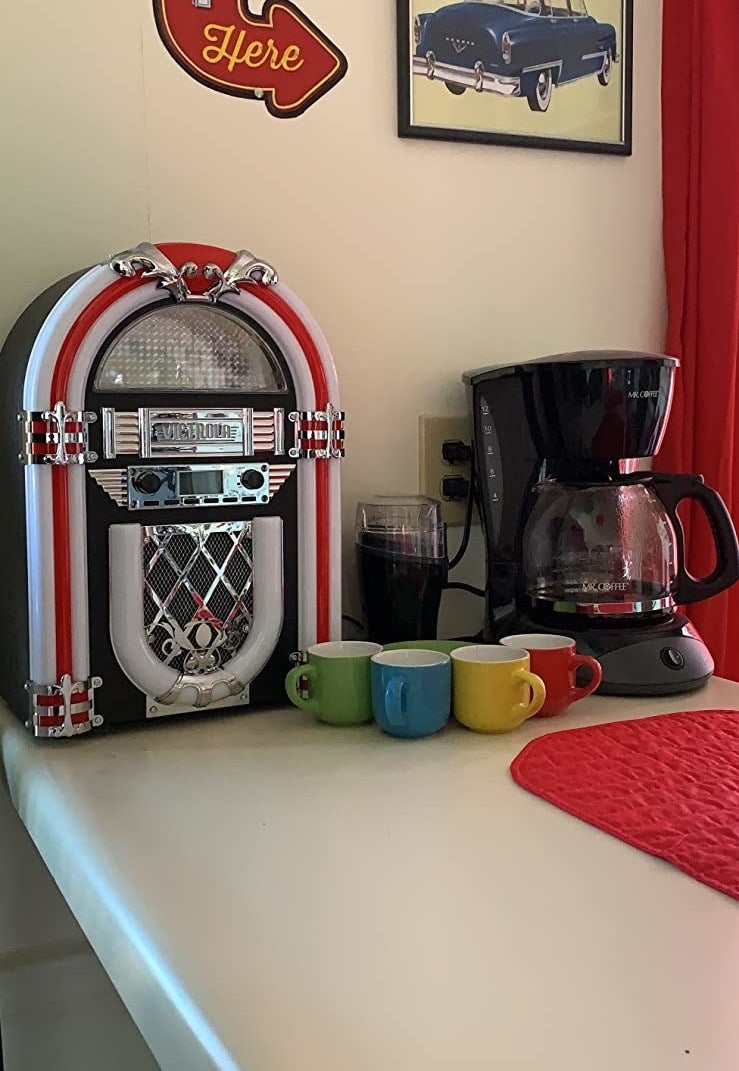 The jukebox sitting  on the counter in a 50&#x27;s themed room