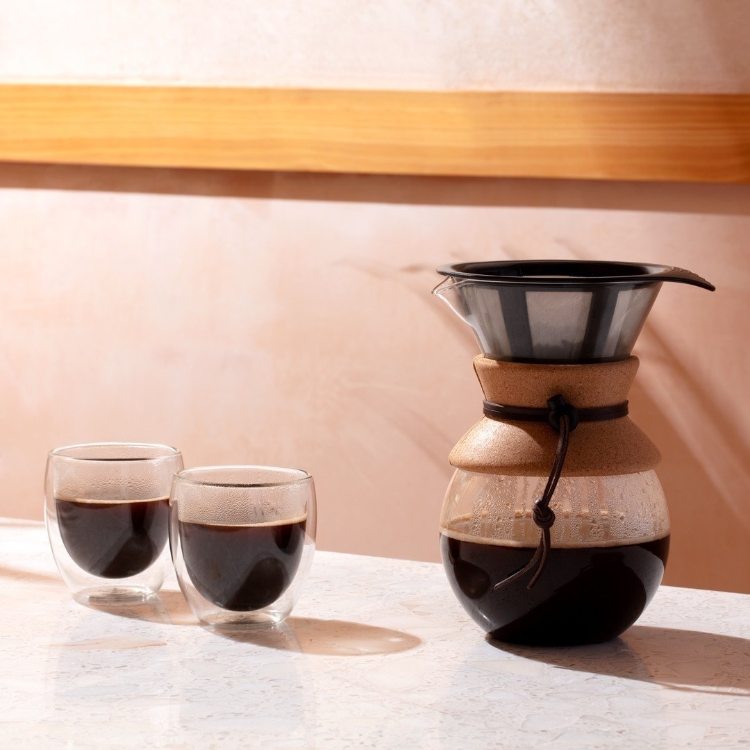 A pour over coffee maker and two small glass cups next to it