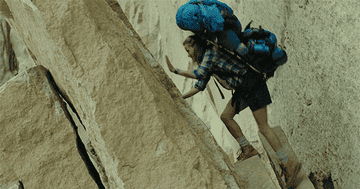 Reese Witherspoon in Wild climbing a rock in her backpacking pack