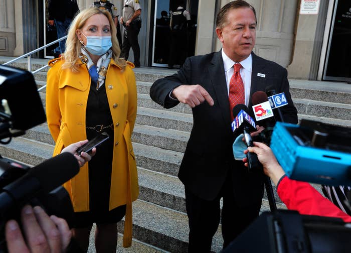 A man and woman speak into reporters' microphones outside a courthouse