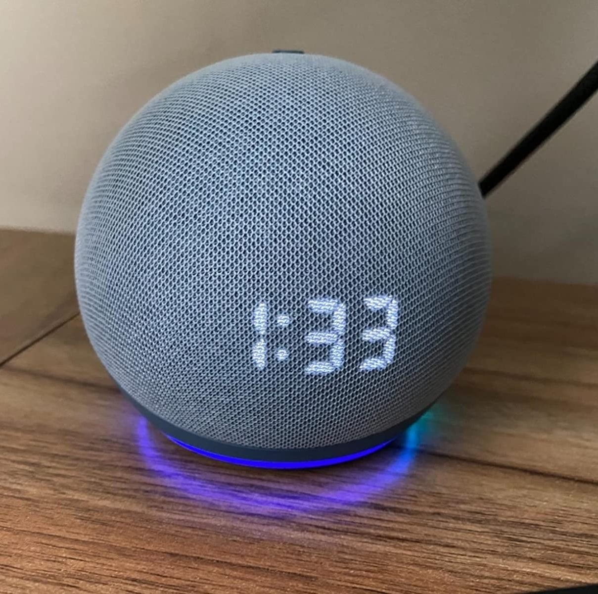 The round Echo Dot with a digital time display on a reviewer&#x27;s night stand