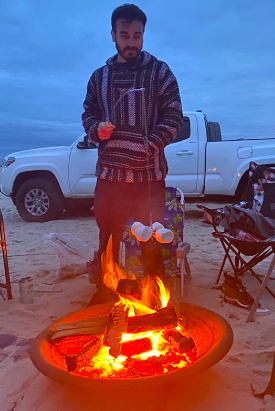 Reviewer holding the fishing pole with marshmallows over the fire 