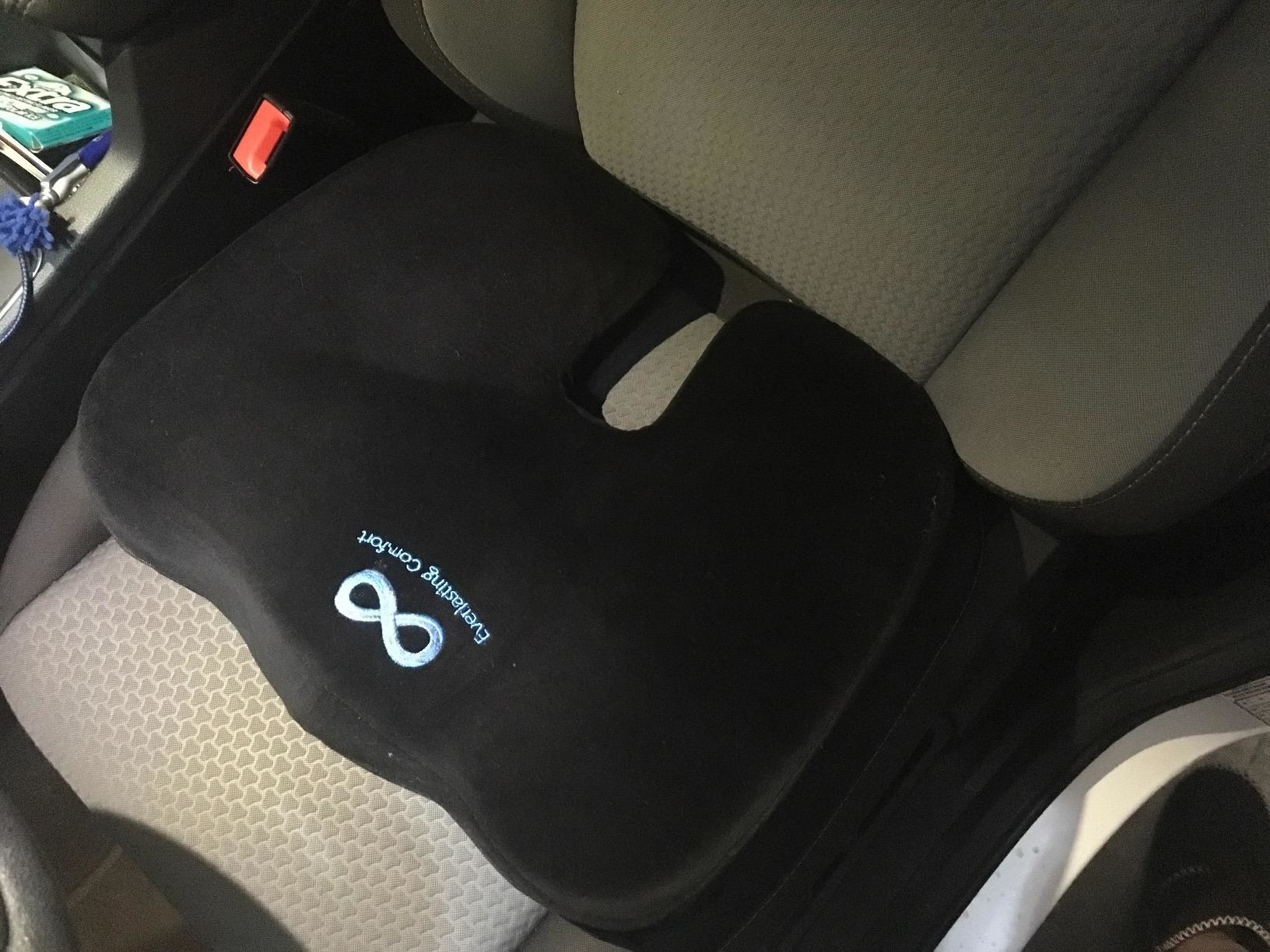 reviewer image of the black everlasting comfort seat cushion on the driver&#x27;s seat of a car
