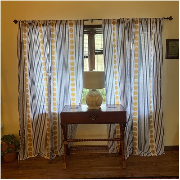 A reviewer photo of the curtains, which are white with blue vertical stripes segments that alternate vertically with segments with mustard yellow dots