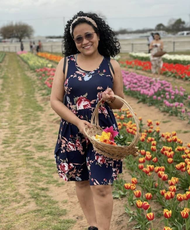 A person wearing a navy blue floral dress in a field of tulips